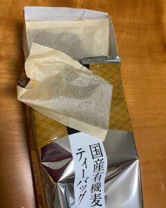 国産有機麦茶ティーバッグの中身。無漂白の生成り色のティーバッグとパッケージ